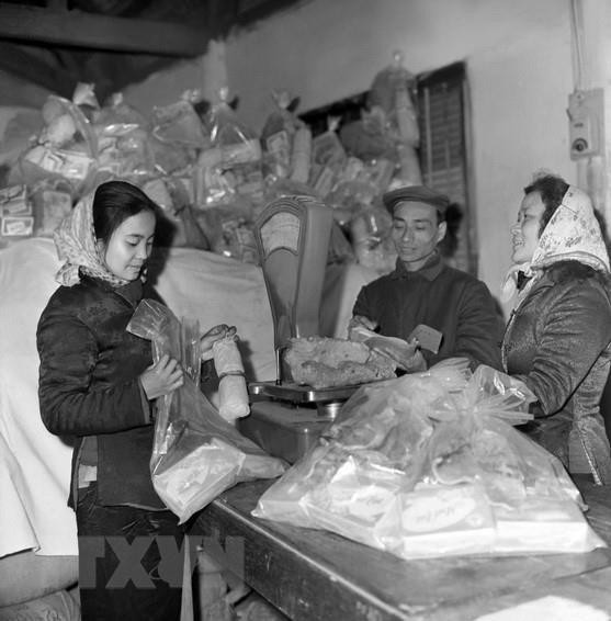 Công ty Bách hóa Bán lẻ Hà Nội tổ chức đóng gói hàng Tết đúng tiêu chuẩn định lượng và điều vận tốt hàng hóa đến bán tại các cửa hàng bách hóa và các quầy hàng tập thể ở cơ quan, xí nghiệp, phục vụ nhân dân trong dịp Tết Canh Tuất 1970. (Ảnh: Trần Phác/TTXVN) Công ty Bách hóa Bán lẻ Hà Nội tổ chức đóng gói hàng Tết đúng tiêu chuẩn định lượng và điều vận tốt hàng hóa đến bán tại các cửa hàng bách hóa và các quầy hàng tập thể ở cơ quan, xí nghiệp, phục vụ nhân dân trong dịp Tết Canh Tuất 1970. (Ảnh: Trần Phác/TTXVN)