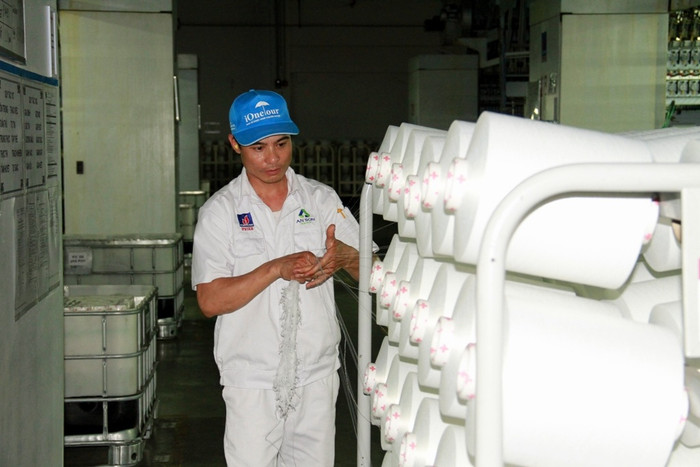 Công nhân kỹ thuật phân xưởng Filament - Nhà máy Xơ sợi Đình Vũ đang lấy đầu mối sợi DTY vừa xuất xưởng Công nhân kỹ thuật phân xưởng Filament - Nhà máy Xơ sợi Đình Vũ đang lấy đầu mối sợi DTY vừa xuất xưởng