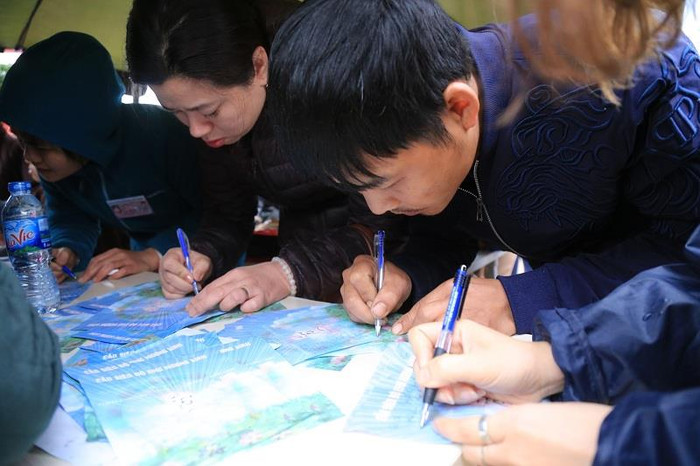 Người hành hương viết tên của chư hương linh lên giấy, nguyện cầu cho chư hương linh được vãn sanh nơi cảnh giới an lành