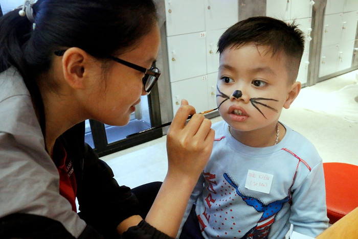 Cô giáo hỗ trợ một bạn nhỏ hóa trang mặt nạ mèo dễ thương Cô giáo hỗ trợ một bạn nhỏ hóa trang mặt nạ mèo dễ thương