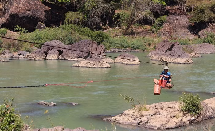 Cả người lớn và trẻ nhỏ vẫn thường phải đu dây qua sông.