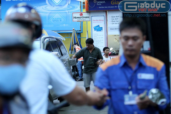 Nhân viên bơm xăng làm việc liên tục nên người người đàn ông đi xe hơi phải tự bơm xăng