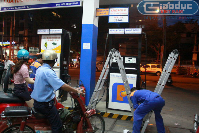 Nhân viên cây xăng chuẩn bị thang để điều chỉnh giá