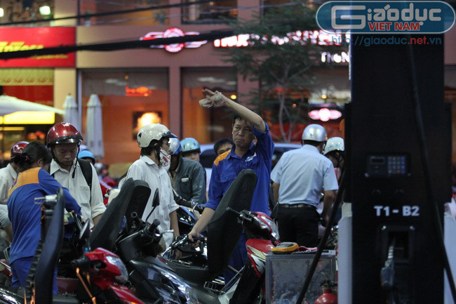 Nhân viên bơm xăng ra hiệu cho thêm nhân viên hỗ trợ bơm xăng