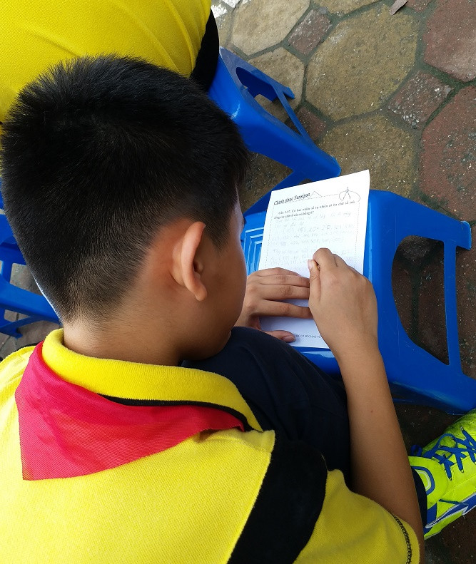 Cậu học trò say mê giải toán ngay trên chiếc ghế. ảnh: Ngọc Quang.