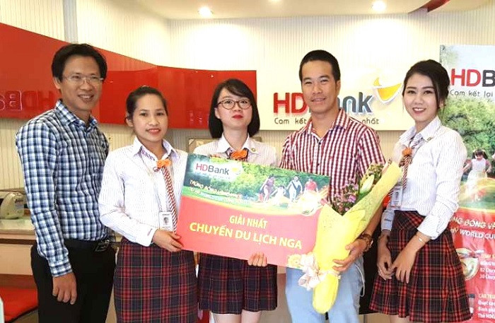Khách hàng Bạch Minh Khoa (thứ hai từ phải sang) giao dịch tại HDBank Lê Quang Định (TP HCM) nhận giải nhất – chuyến du lịch xem WorldCup 2018 tại Nga trị giá 50 triệu đồng. Khách hàng Bạch Minh Khoa (thứ hai từ phải sang) giao dịch tại HDBank Lê Quang Định (TP HCM) nhận giải nhất – chuyến du lịch xem WorldCup 2018 tại Nga trị giá 50 triệu đồng.