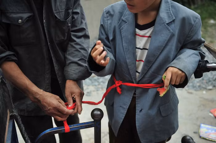 Hai ông cháu này đến từ Tín Dương, Hà Nam và sinh sống bằng nghề nhặt rác. Bị mắc chứng động kinh và chậm phát triển tâm thần, Jiang Manqi,13 tuổi, đã thường xuyên bị buộc vào một sợi dây nối với chiếc xe ba bánh trong lúc ông nội đi nhặt rác trên đường. Hai ông cháu này đến từ Tín Dương, Hà Nam và sinh sống bằng nghề nhặt rác. Bị mắc chứng động kinh và chậm phát triển tâm thần, Jiang Manqi,13 tuổi, đã thường xuyên bị buộc vào một sợi dây nối với chiếc xe ba bánh trong lúc ông nội đi nhặt rác trên đường.