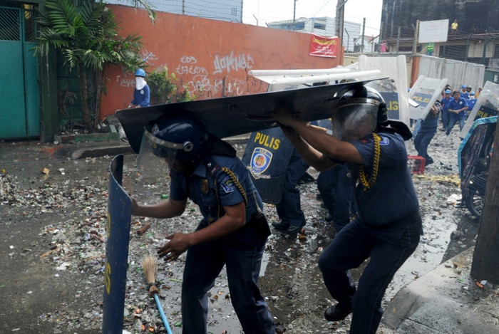 Các cảnh sát cố gắng né tránh những viên gạch và chai lọ mà người dân ném đến. Các cảnh sát cố gắng né tránh những viên gạch và chai lọ mà người dân ném đến.