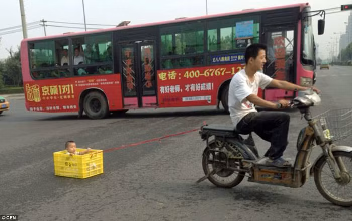 Đứa bé bị đặt trong thùng đựng đồ uống và gắn với xe máy bằng một sợi dây.