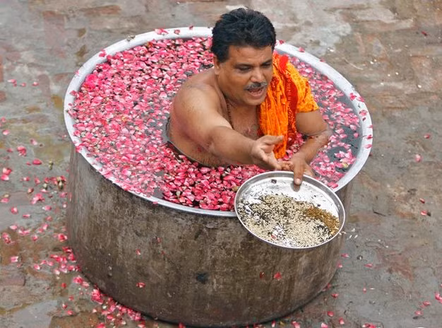 Ở thành phố Ahmedabad, một giáo sĩ Hindu ngồi trong một chiếc nồi lớn chứa đầy nước và cánh hoa, để cầu nguyện trong buổi lễ cầu mưa.