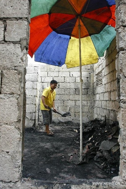 Một người đàn ông đang dọn dẹp căn nhà tồi tàn sau hỏa hoạn.