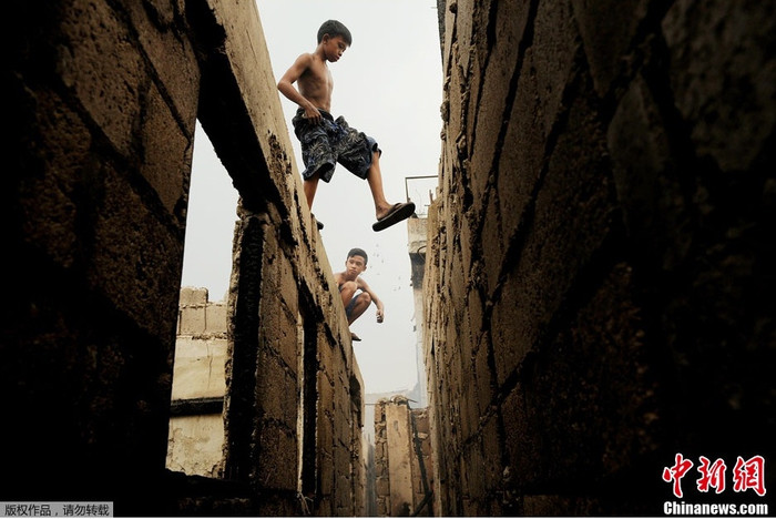 Những đứa trẻ liều lình đi trên những bước tường còn lại sau đám cháy.