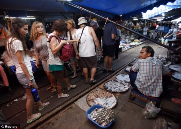 Kẻ mua người bán vẫn điềm tĩnh đi lại trên đường ray.