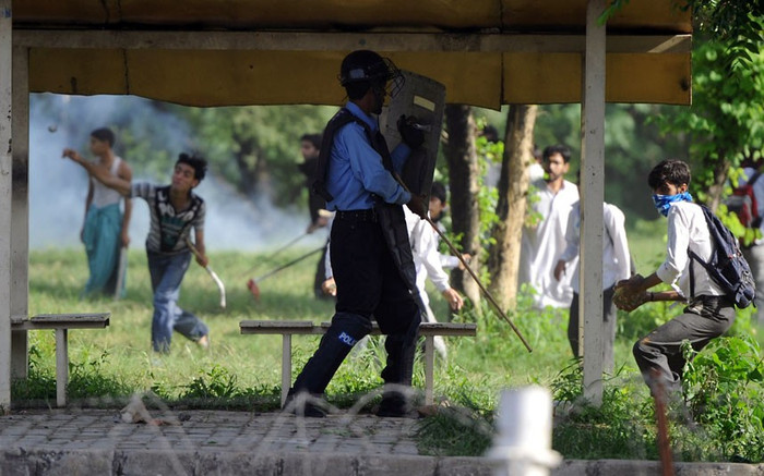 Một cảnh sát đang cố tránh khi một người biểu tình muốn ném đá vào anh. Một cảnh sát đang cố tránh khi một người biểu tình muốn ném đá vào anh.