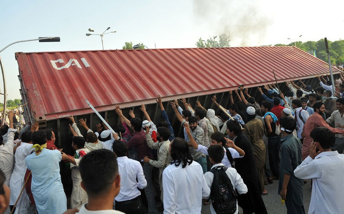 Đám đông lật đổ container vận chuyển hàng hóa được cảnh sát đặt để làm rào chắn ngăn chặn con đường vào Đại sứ quán Mỹ. Đám đông lật đổ container vận chuyển hàng hóa được cảnh sát đặt để làm rào chắn ngăn chặn con đường vào Đại sứ quán Mỹ.