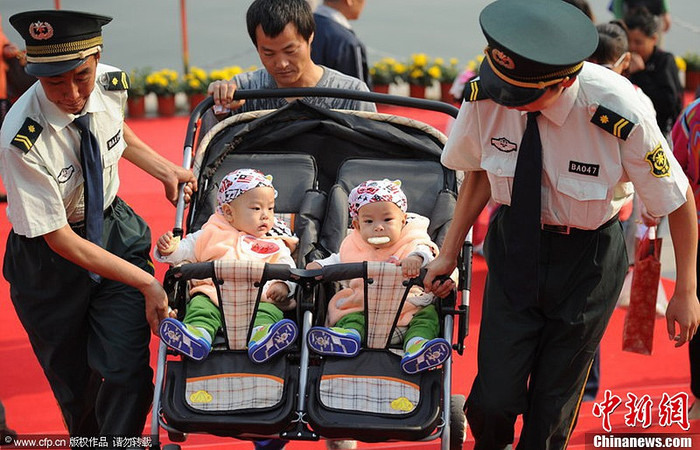 Các nhân viên an ninh giúp một người bố đưa hai em bé lên bậc thang. Các nhân viên an ninh giúp một người bố đưa hai em bé lên bậc thang.