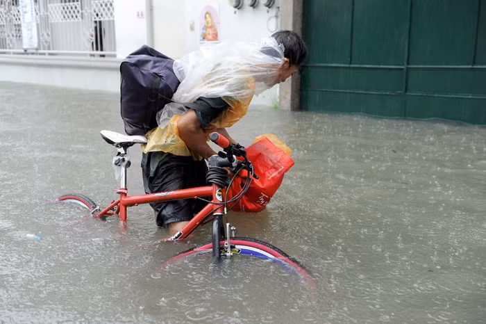 Một người dân đang cố đẩy chiếc xe đạp ra khỏi dòng nước.