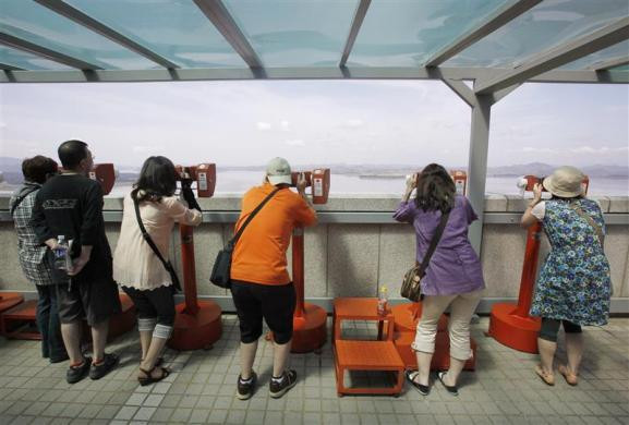 Khách du lịch Nhật Bản đang nhìn ngôi làng ở quận Kaepoong của Triều Tiên qua ống nhòm trên đài quan sát Hàn Quốc gần khu phi quân sự ngăn cách hai miền Triều Tiên ở Paju, phía bắc Seoul.