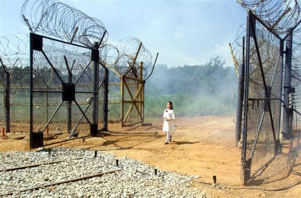 Trên tay cầm một bông hoa, bé gái đi qua cánh cổng dẫn vào khu phi quân sự.