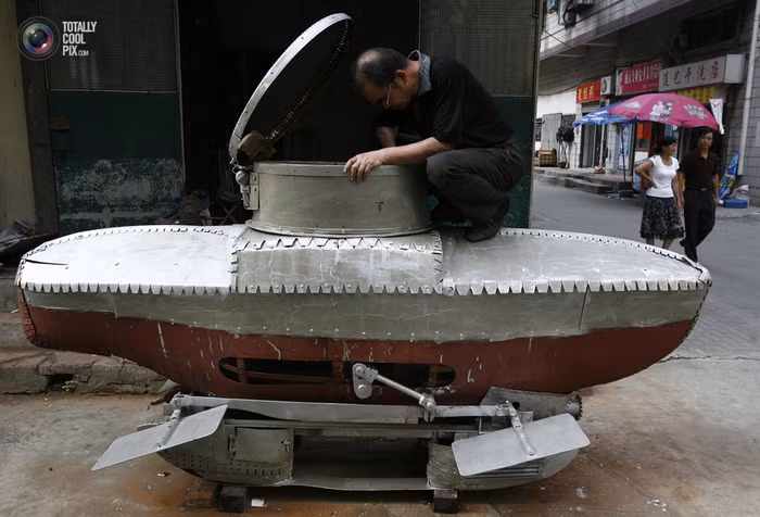 Lý Ngọc Minh với chiếc tàu ngầm thu nhỏ chưa hoàn thiện ở vùng ngoại ô Vũ Hán, thủ phủ của tỉnh Hồ Bắc. Nó có tên là Hà Quang V (ánh sáng cầu vồng 5), dài 3m, cao 1,2m, có thể lặn ở độ sâu tối đa 20m và có thể chứa hai người lớn và một trẻ em cùng một lúc.