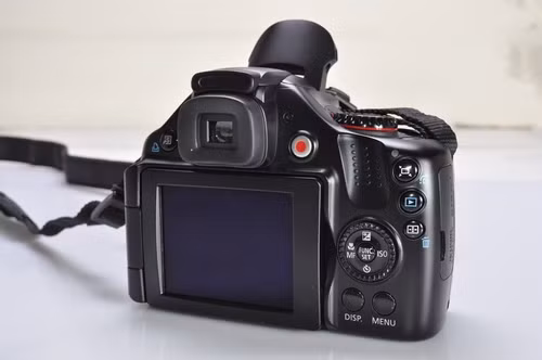 Điểm đặc biệt của phiên bản siêu zoom này là nút chức năng lấy khuôn hình (bố trí ngay phía trên nút xem lại hình) - rất tiện lợi để xác định đối tượng mỗi khi người dùng zoom đến mức tiêu cự tối đa.