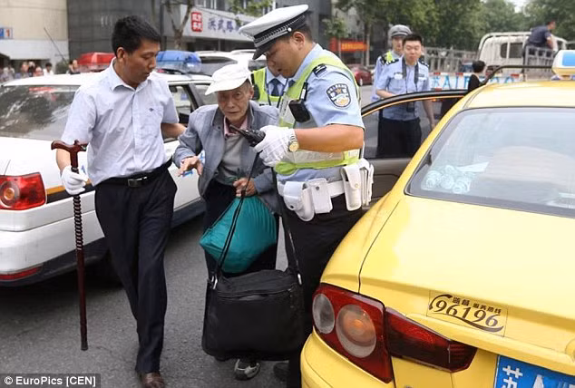 Người lái xe và cảnh sát giúp đỡ ông cụ vào phòng thi.