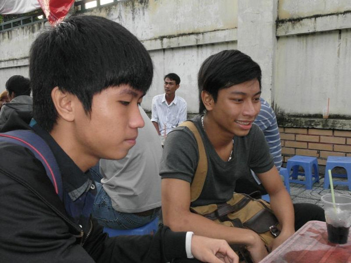 Hai thí sinh Đặng Đức Duy, Dương Thái Sơn thoái mái ngồi uống cà phê trong khi mọi người đang vào phòng thi. Ảnh chụp trước điểm thi của trường CĐ Bách Việt. Ảnh: Dương Cầm