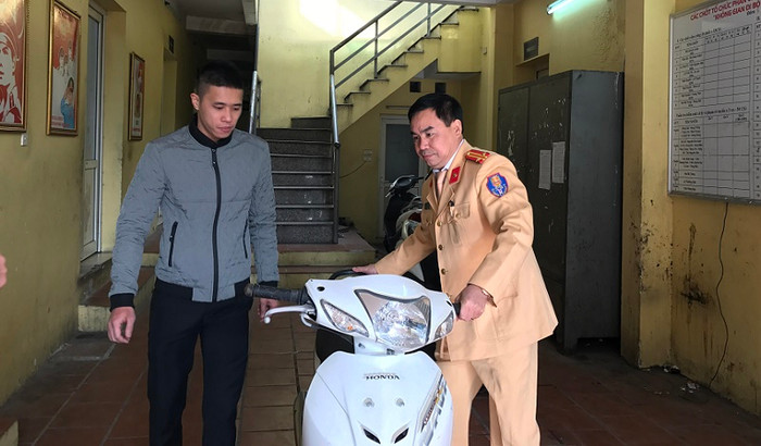 Trung tá Thiều Mạnh Ngọc dắt xe trao trả cho anh Nguyễn Đức Hiếu. ảnh: NQ.