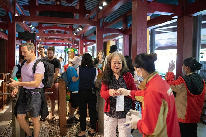 Nhân viên tại Bà Nà Hills phát khẩu trang miễn phí và hướng dẫn du khách đeo khẩu trang đúng cách.