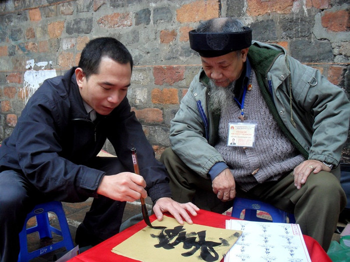 Khách xem chữ thử cầm bút lông. Khách xem chữ thử cầm bút lông.