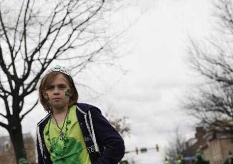 Một em nhỏ vẽ cỏ ba lá lên mặt và mặc trang phục màu xanh Ireland chào mừng ngày lễ Thánh Patrick