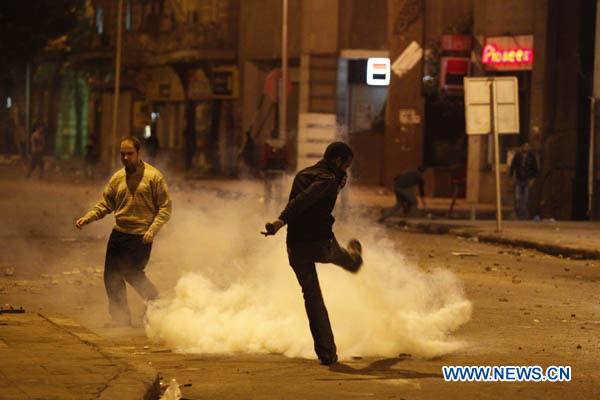 Một người biểu đình đá quả đạn khói của cảnh sát trở lại