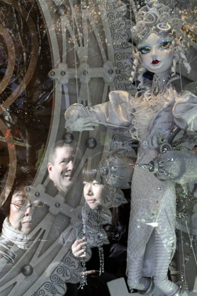 Một người qua đường đang ngắm bức tượng Giáng sinh qua ô cửa kính của một cửa hàng trên quảng trường Herald, New York Một người qua đường đang ngắm bức tượng Giáng sinh qua ô cửa kính của một cửa hàng trên quảng trường Herald, New York