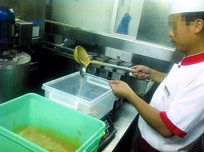 Nhân viên nhà hàng Haidibao tại Thành Đô đang lấy bột nhão trong hộp màu xanh để pha chế nước lẩu.