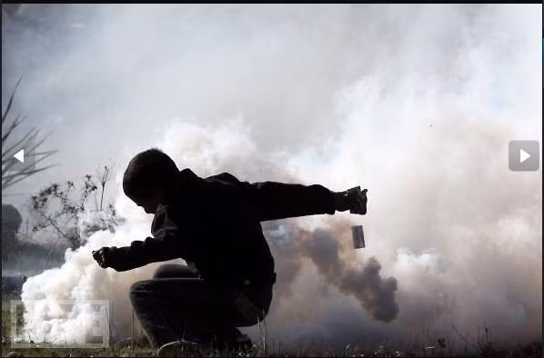 Một cậu bé Palestine đang cố lấy ống hơi cay cảnh sát ném ra trong cuộc biểu tình tại làng West Bank, Nabi Saleh.