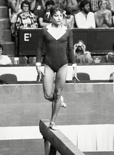 Olga Korbut của Nga, Munich, 1972. Bộ quần áo thể dục dụng cụ bó sát gần như mang tính công sở với tay và cổ áo theo kiểu sơ mi, kết hợp với kiểu tóc buộc những năm 70 đã tạo nên dấu ấn riêng cho cô gái 17 tuổi Olga Korbut. Olga Korbut của Nga, Munich, 1972. Bộ quần áo thể dục dụng cụ bó sát gần như mang tính công sở với tay và cổ áo theo kiểu sơ mi, kết hợp với kiểu tóc buộc những năm 70 đã tạo nên dấu ấn riêng cho cô gái 17 tuổi Olga Korbut.