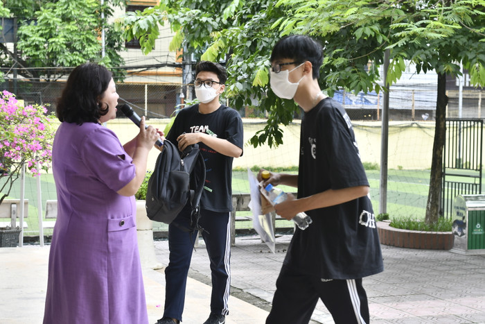 Cô Cao Thanh Nga - Phó Điểm trưởng Điểm thi Trường Trung học phổ thông Phan Huy Chú – Đống Đa hướng dẫn thí sinh di chuyển đến khu vực để đồ dùng không cần thiết. (Ảnh: Ngọc Mai).