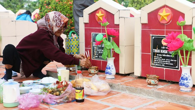 Mẹ Nguyễn Thị Tý thắp hương trước phần mộ con trai tại Nghĩa trang liệt sỹ tỉnh An Giang. (Ảnh Công Mạo/TTXVN).
