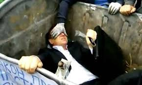 Ông Vitaly Zhuravskyi bị ấn xuống thùng rác và bị ném trứng mỗi lần ông cố gắng đứng dậy thoát ra ngoài. Ông Vitaly Zhuravskyi bị ấn xuống thùng rác và bị ném trứng mỗi lần ông cố gắng đứng dậy thoát ra ngoài.