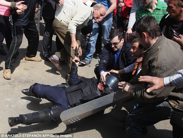 Một cảnh sát chống bạo động bị đám đông người biểu tình giận dữ tấn công.