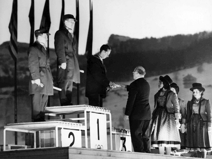 Chủ tịch Ủy ban Olympic Quốc tế Avery Brundage trao huy chương cho các vận động viên thi môn Ski Jump tại Cortina, Ý năm 1956. Từ trái sang phải: Aulis Kallakorpi (Phần Lan) giành huy chương bạc; Antti Hyvarinen (Phần Lan) giành Huy chương vàng; Harry Glasss (Đông Đức) giành Huy chương đồng.