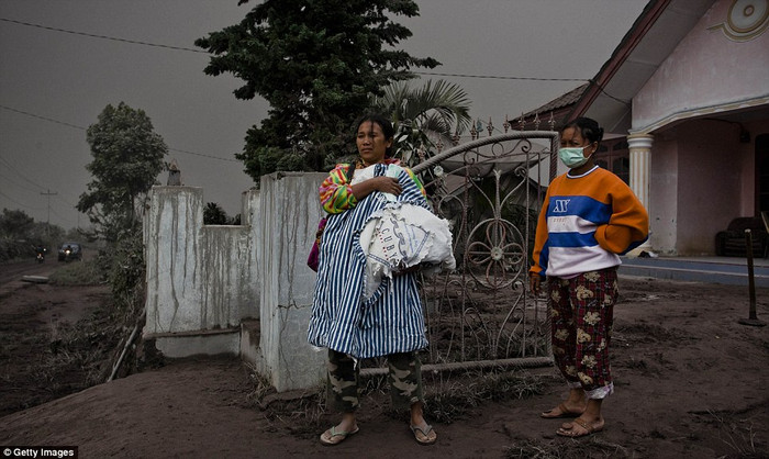 Một phụ nữ ôm con nhỏ chờ sơ tán.