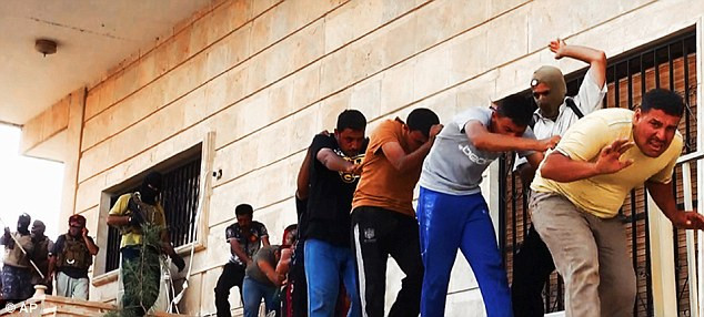 Một tay súng đeo mặt nạ đe dọa các tù nhân.