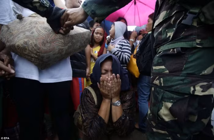 Một phụ nữ ngồi xụp xuống đất òa khóc khi không thể tới được chỗ máy bay di tản