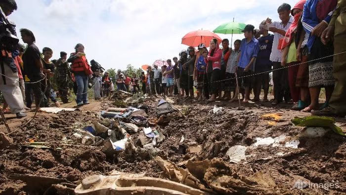 Xác máy bay, hành lí của nạn nhân rơi vãi trên nền đất, nơi máy bay va chạm trước khi lao xuống sông.