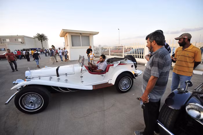 Du khách xem một người đàn ông ngồi trong chiếc xe Mercedes-Benz cổ tại triển lãm xe hơi ở Benghazi ngày 3/7/2013.