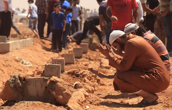 Một người đàn ông cầu nguyện bên cạnh những ngôi mộ trong đám tang của những người thiệt mạng trong cuộc đụng độ tại trụ sở lữ đoàn Shield ở Benghazi ngày 9/6/2013. Quân đội Libya đã kiểm soát căn cứ lực lượng dân quân này sau cuộc đụng độ làm 31 người đã thiệt mạng giữa những người biểu tình đòi giản tán lực lượng dân quân đã tồn tại gần 2 năm sau khi chính quyền Gaddafi sụp đổ.