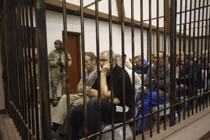 Những người đàn ông thuộc các nước Liên Xô cũ ngồi trong song sắt trong buổi điều trần kháng cáo tại Tòa án quân sự tối cao Libya ở Tripoli ngày 29/5/2013. Họ bị báo buộc làm lính đánh thuê cho Gaddafi trong cuộc xung đột năm 2011.