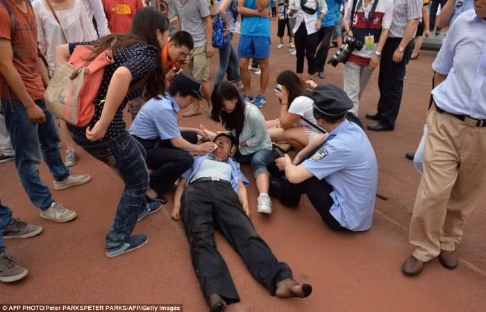 Nữ cảnh sát được đồng đội và các sinh viên giúp đỡ sau khi bị thương trong đám đông.