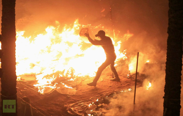 Một người biểu tình cố gắng dập lửa trên chiếc lều bị đốt cháy bởi cảnh sát tại Cairo ngày 25/1.